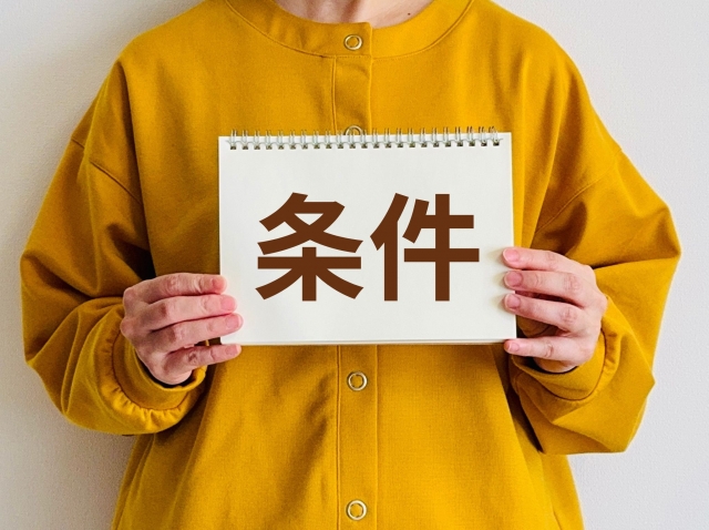 条件と書かれた紙を持つ女性